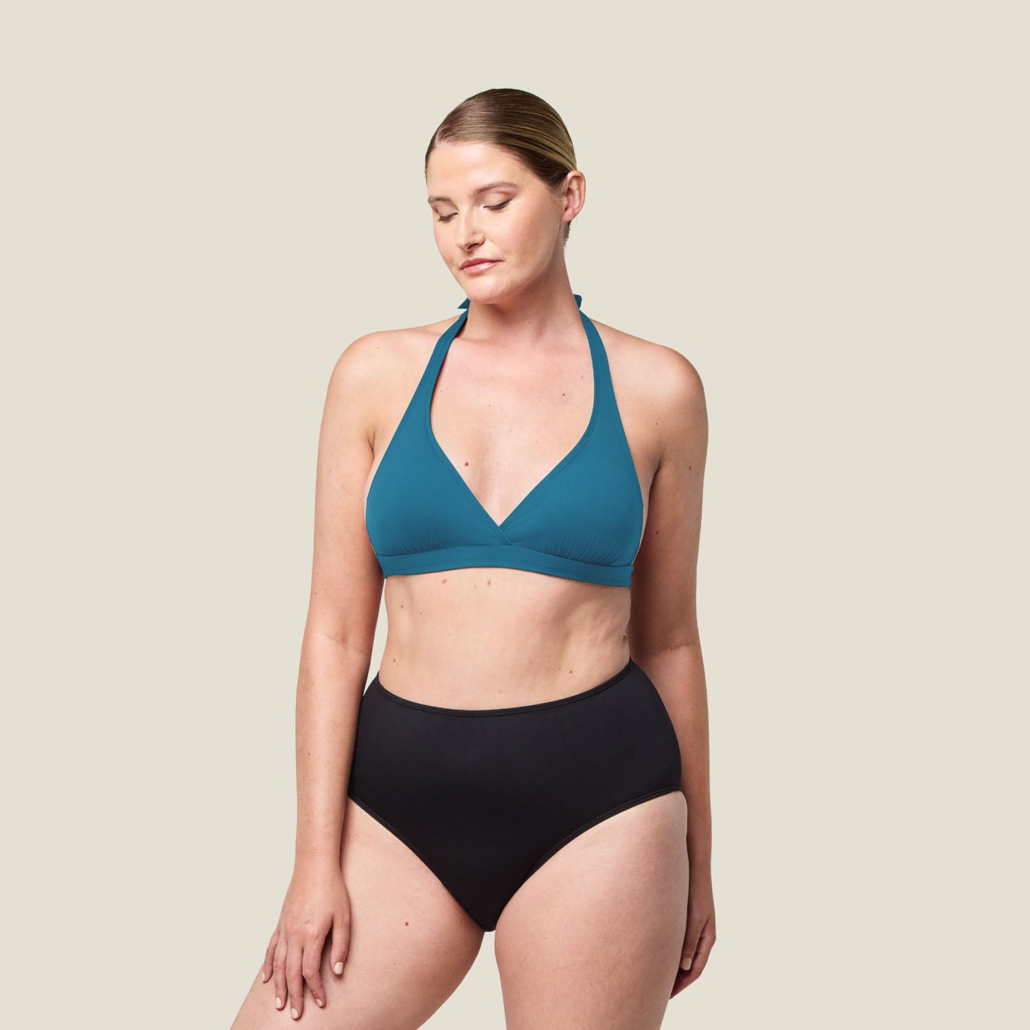 Full-length image of woman wearing WUKA Tie-Back Bikini Top in blue, showcasing supportive halter neck design and high-waisted black swim bottoms.