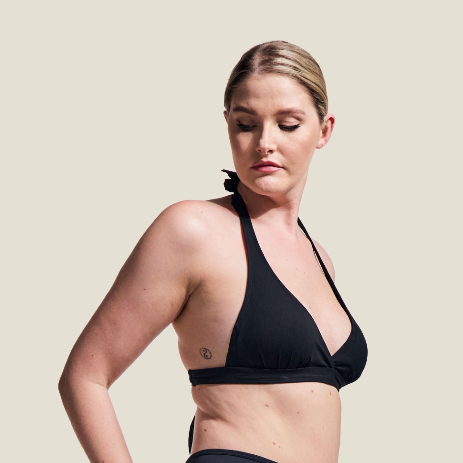 Side profile of model wearing WUKA black tie-back bikini top, highlighting side coverage and support.
