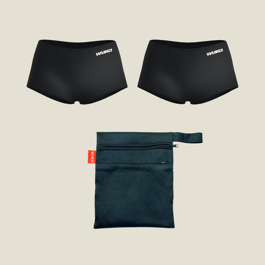 Flat lay of WUKA Teen Sleep Stretch™ Boxer Heavy Set 2 Pack with two black boxer-style period pants and a matching reusable wet bag, ideal for teens during menstruation.