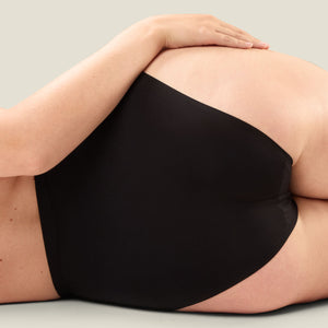 Close-up lifestyle shot of WUKA high-waist seamless heavy flow period pants worn by model lying down, showcasing comfort and body-hugging fit.